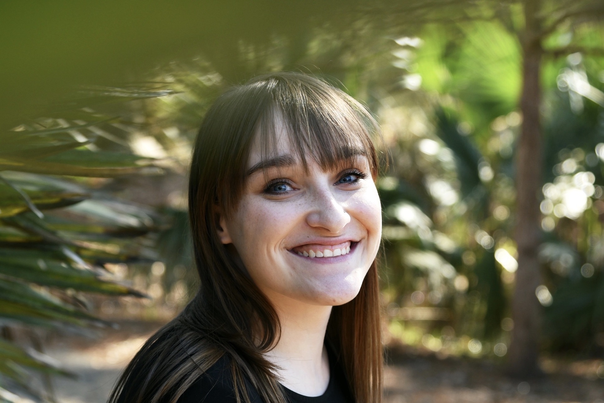 A white woman smiling in front of trees